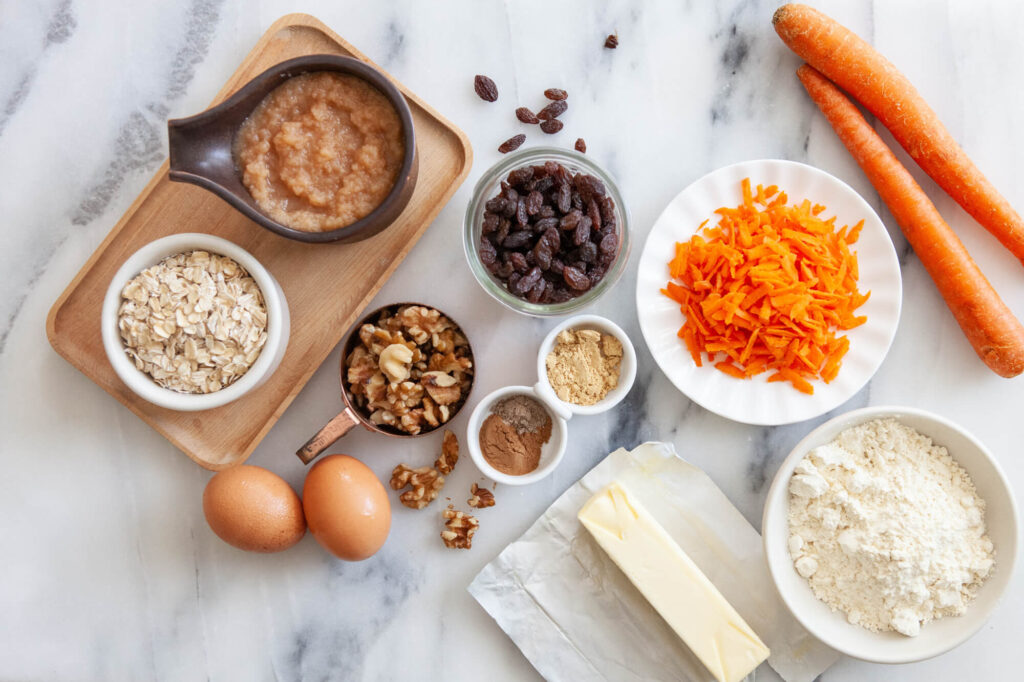 ingredients for carrot cake muffins with homemade butter arranged on counter top