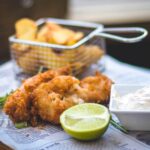 Fried Fish with a lime and horseradish with chips in the background in a metal basket
