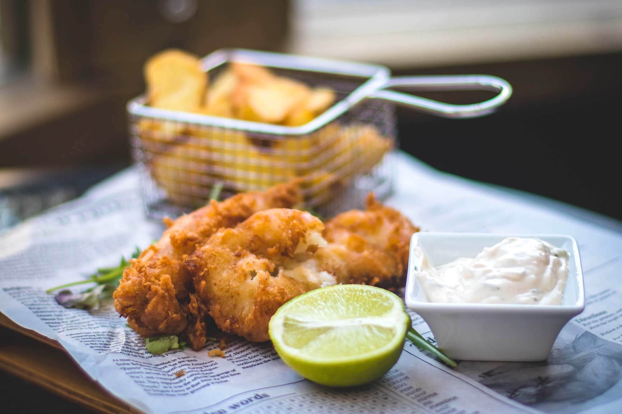 Fried Fish with a lime and horseradish with chips in the background in a metal basket