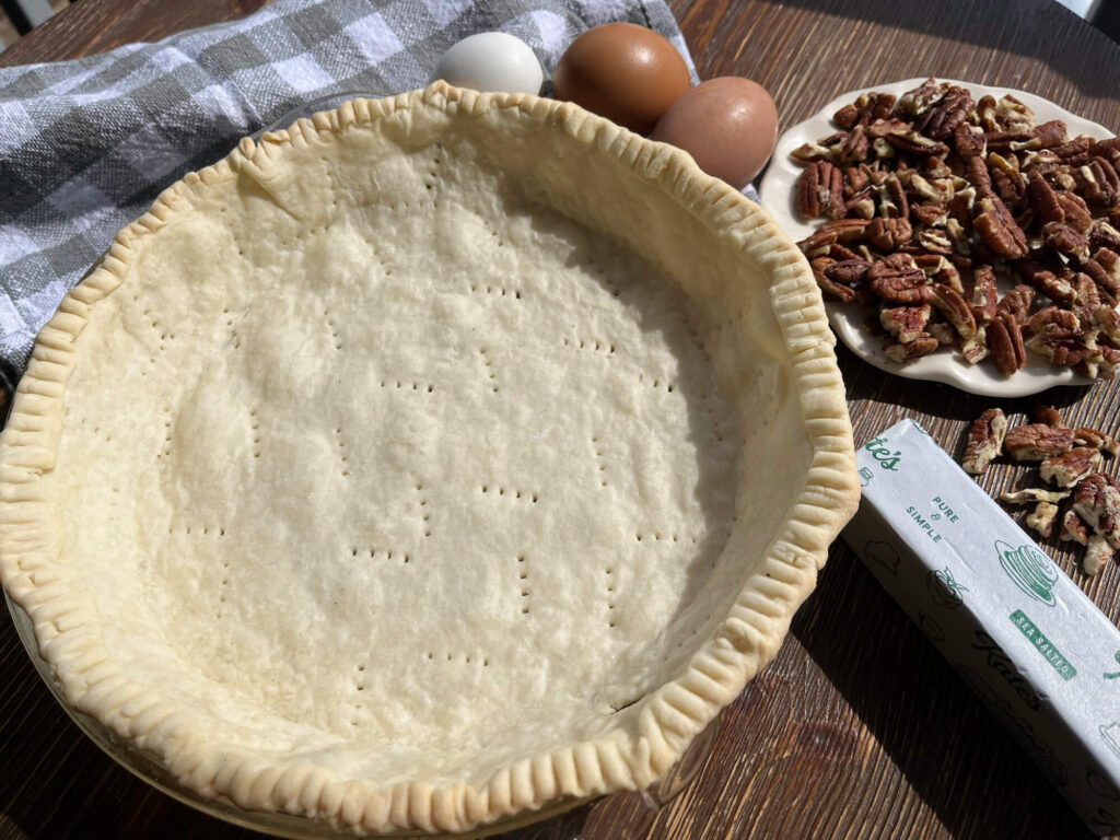pie crust next to a bowl of pecans