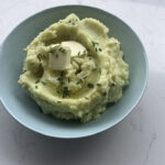 Mashed potatoes topped with a square of butter sitting in a bowl