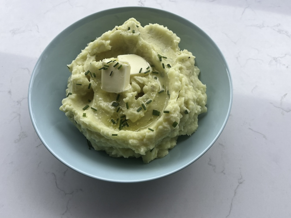 Mashed potatoes topped with a square of butter sitting in a bowl