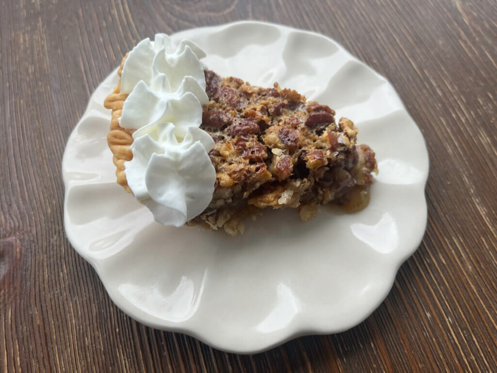 A slice of pecan pie with whipped cream