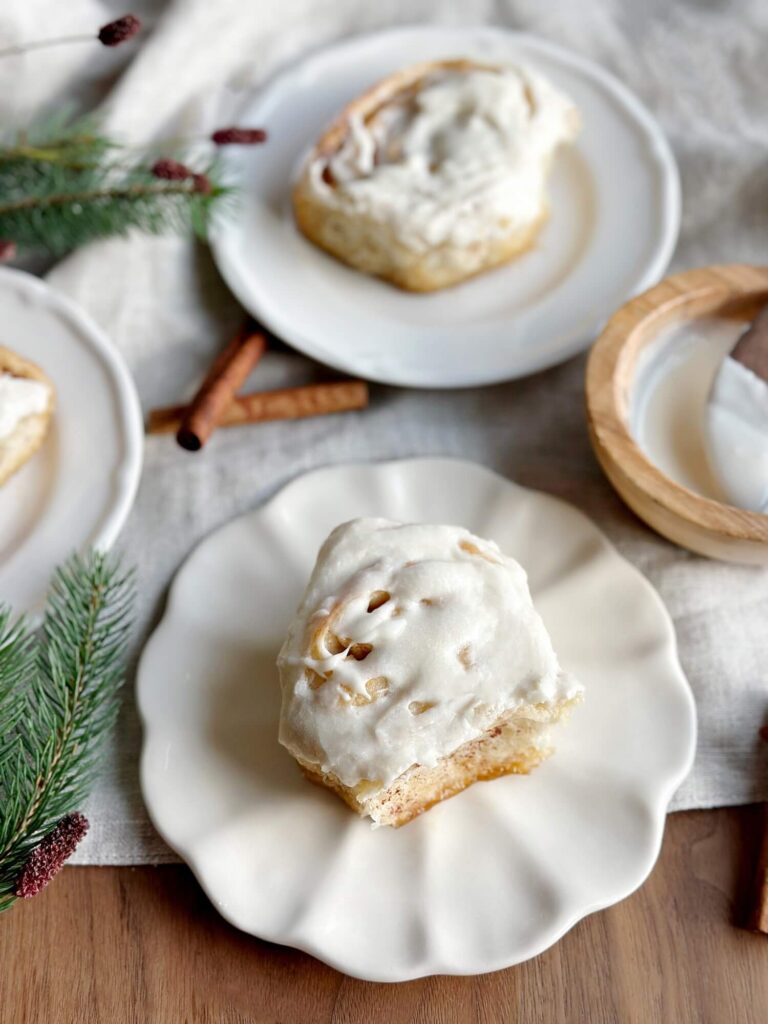 Cinnamon roll with icing on it sitting on a plate with a bite taken out of it